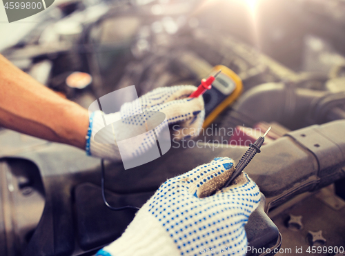 Image of auto mechanic man with multimeter testing battery