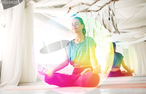 Image of woman meditating in lotus pose at yoga studio