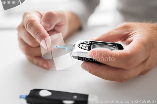 Image of senior man with glucometer checking blood sugar