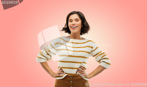 Image of smiling woman in pullover with hands on hips