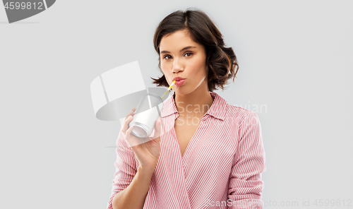 Image of woman drinking soda from can with paper straw