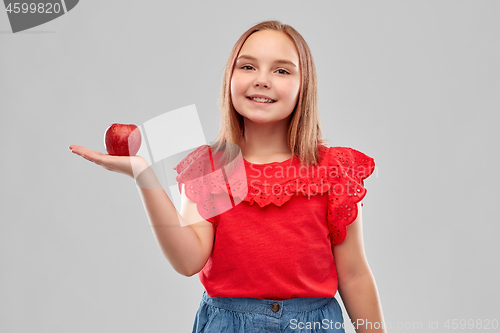 Image of beautiful smiling girl holding red apple on palm