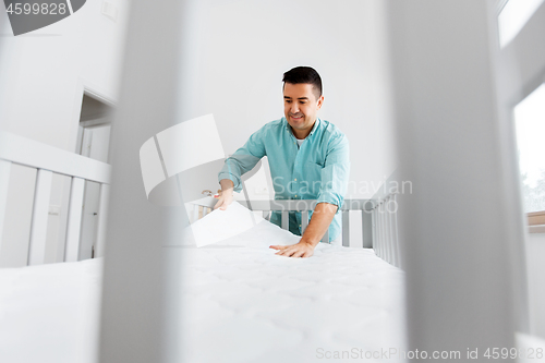 Image of father arranging baby bed with mattress at home