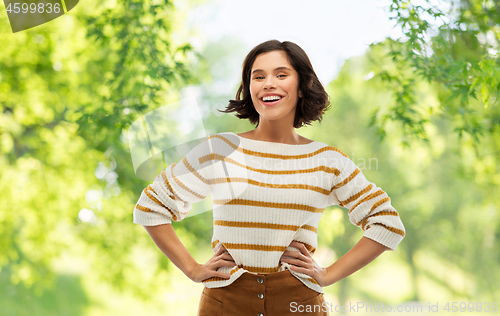 Image of smiling woman in pullover with hands on hips