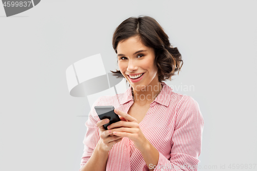 Image of young woman in striped shirt using smartphone