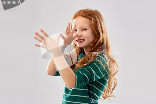 Image of red haired girl having fun and making big nose