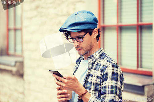 Image of man with smartphone drinking coffee on city street