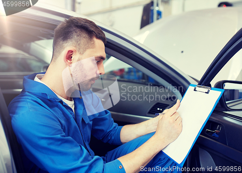 Image of auto mechanic man with clipboard at car workshop