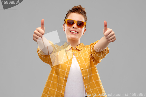 Image of happy teenage girl in sunglasses showing thumbs up