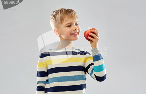 Image of smiling boy in striped pullover eating red apple
