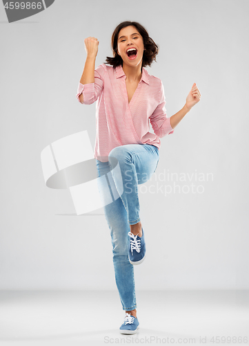 Image of young woman in shirt and jeans celebrating success
