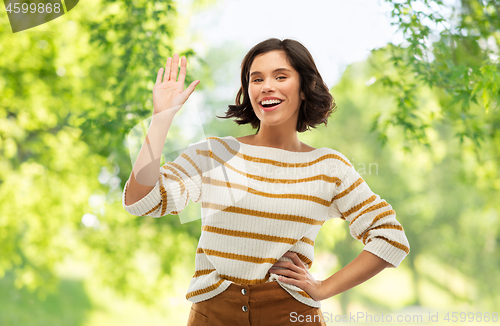 Image of smiling woman in striped pullover waving hand