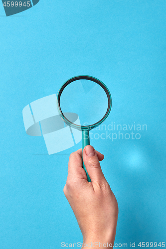 Image of Woman\'s hand with loupe and whadows from it.