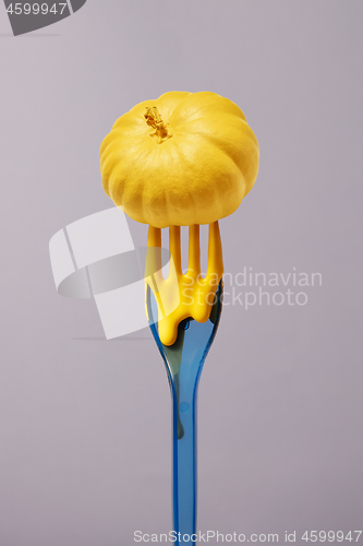 Image of Painted small yellow pumpkin on a vertical plastic fork.