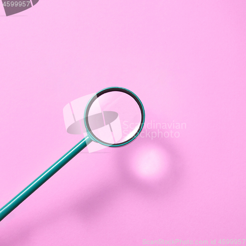 Image of Magnifying glass above pink background with shadows.