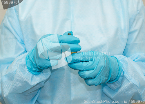 Image of Nurse in sterile gown and gloves with an ampoule with is ready to open it