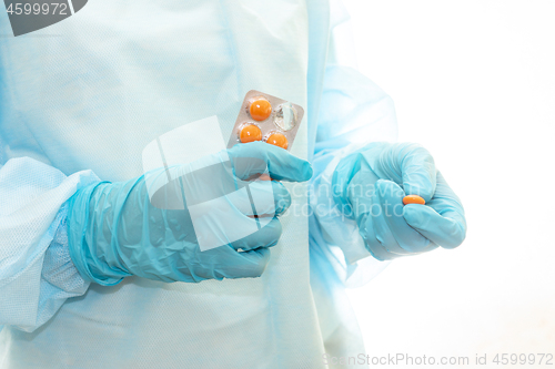 Image of Nurse in sterile gown and gloves gives pill from pack