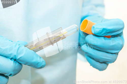 Image of Hands of nurse in sterile gown and gloves take a thermometer out of case