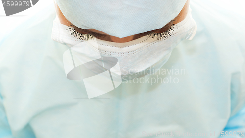 Image of Fluffy eyelashes of surgeon in sterile surgical mask and medical gown at work