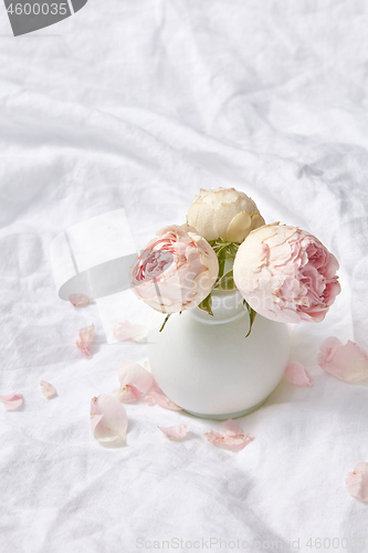 Image of Ceramic vase with roses on a sheet.