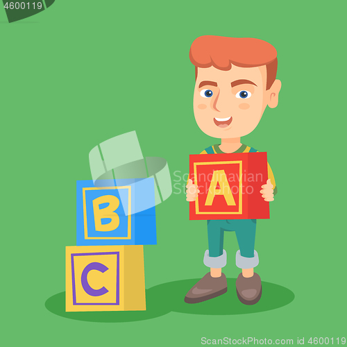 Image of Smiling caucasian boy playing with alphabet cubes.