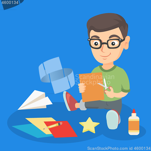 Image of Little boy crafting with scissors and color paper.