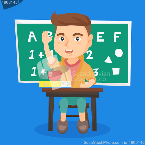 Image of Schoolboy raising hand while sitting at the desk.