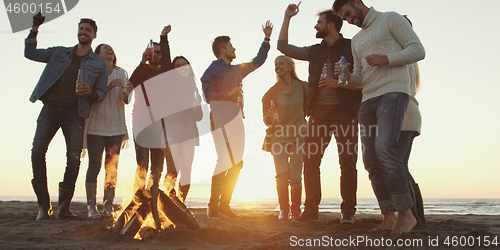 Image of Friends having fun at beach on autumn day