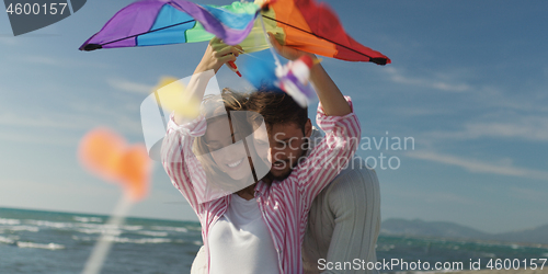 Image of Happy couple having fun with kite on beach