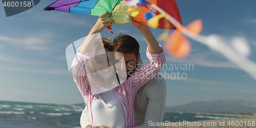 Image of Happy couple having fun with kite on beach