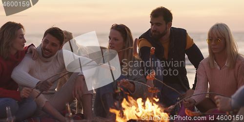 Image of Group Of Young Friends Sitting By The Fire at beach