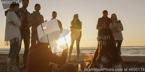 Image of Friends having fun at beach on autumn day