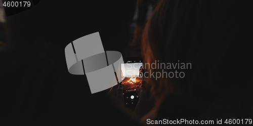 Image of Couple taking photos beside campfire on beach