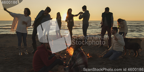 Image of Friends having fun at beach on autumn day