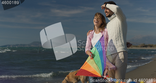 Image of Happy couple having fun with kite on beach