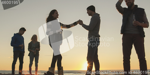 Image of Friends having fun at beach on autumn day