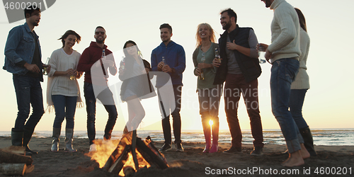 Image of Friends having fun at beach on autumn day