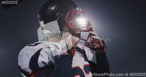 Image of American Football Player Putting On Helmet on large stadium with