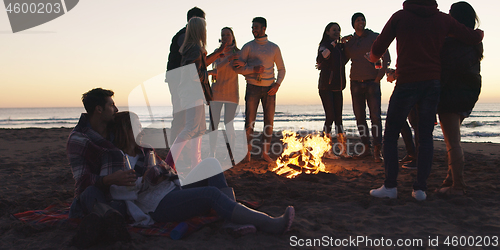 Image of Friends having fun at beach on autumn day