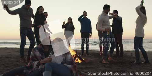 Image of Friends having fun at beach on autumn day