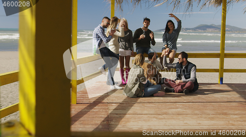 Image of Group of friends having fun on autumn day at beach