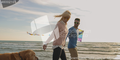 Image of couple with dog having fun on beach on autmun day