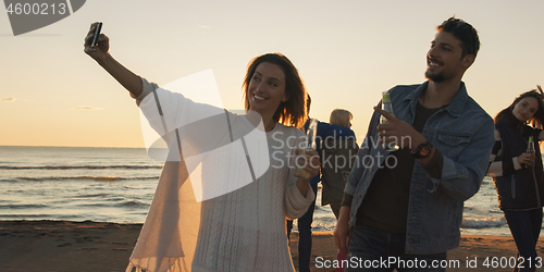 Image of Group of friends having fun on beach during autumn day