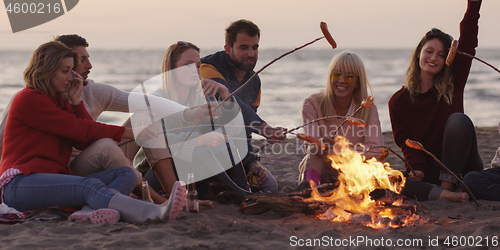 Image of Group Of Young Friends Sitting By The Fire at beach