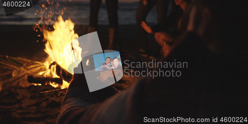 Image of Couple taking photos beside campfire on beach