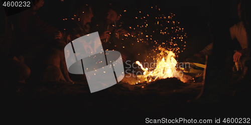 Image of Couple enjoying with friends at night on the beach