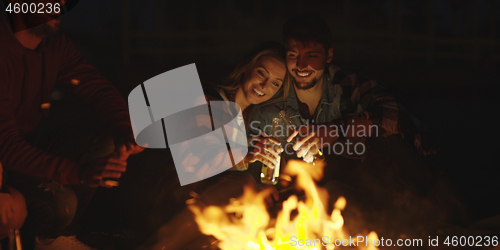 Image of Couple enjoying with friends at night on the beach