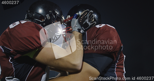 Image of American football players knocking with helmets and having fun