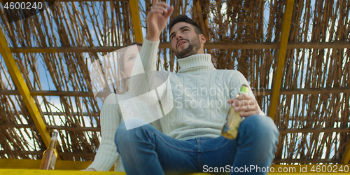 Image of Couple drinking beer together at the beach