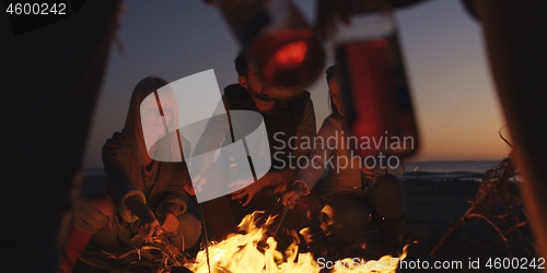 Image of Young Friends Making A Toast With Beer Around Campfire at beach